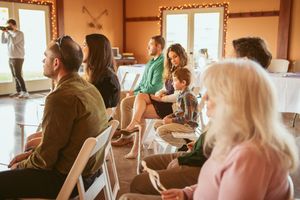 Wedding guests seated in rows of white chairs during an indoor ceremony.