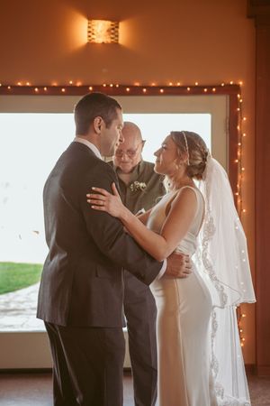 A wedding ceremony with string lights and a warm ambiance as a couple exchanges vows.