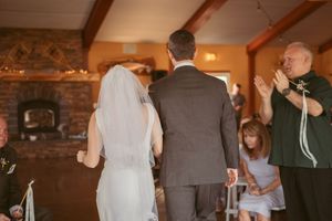 A wedding ceremony takes place in a rustic venue with exposed stone walls and wooden beams.