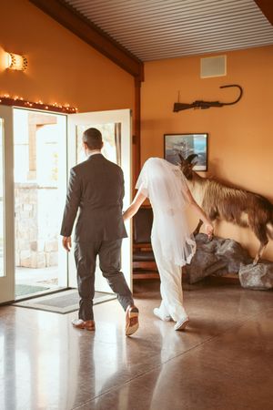 Newlyweds walking through doorway together after ceremony in rustic venue.