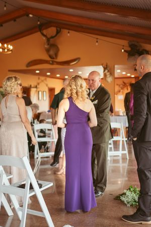 Wedding party gathered in rustic venue decorated with string lights and mounted decor.