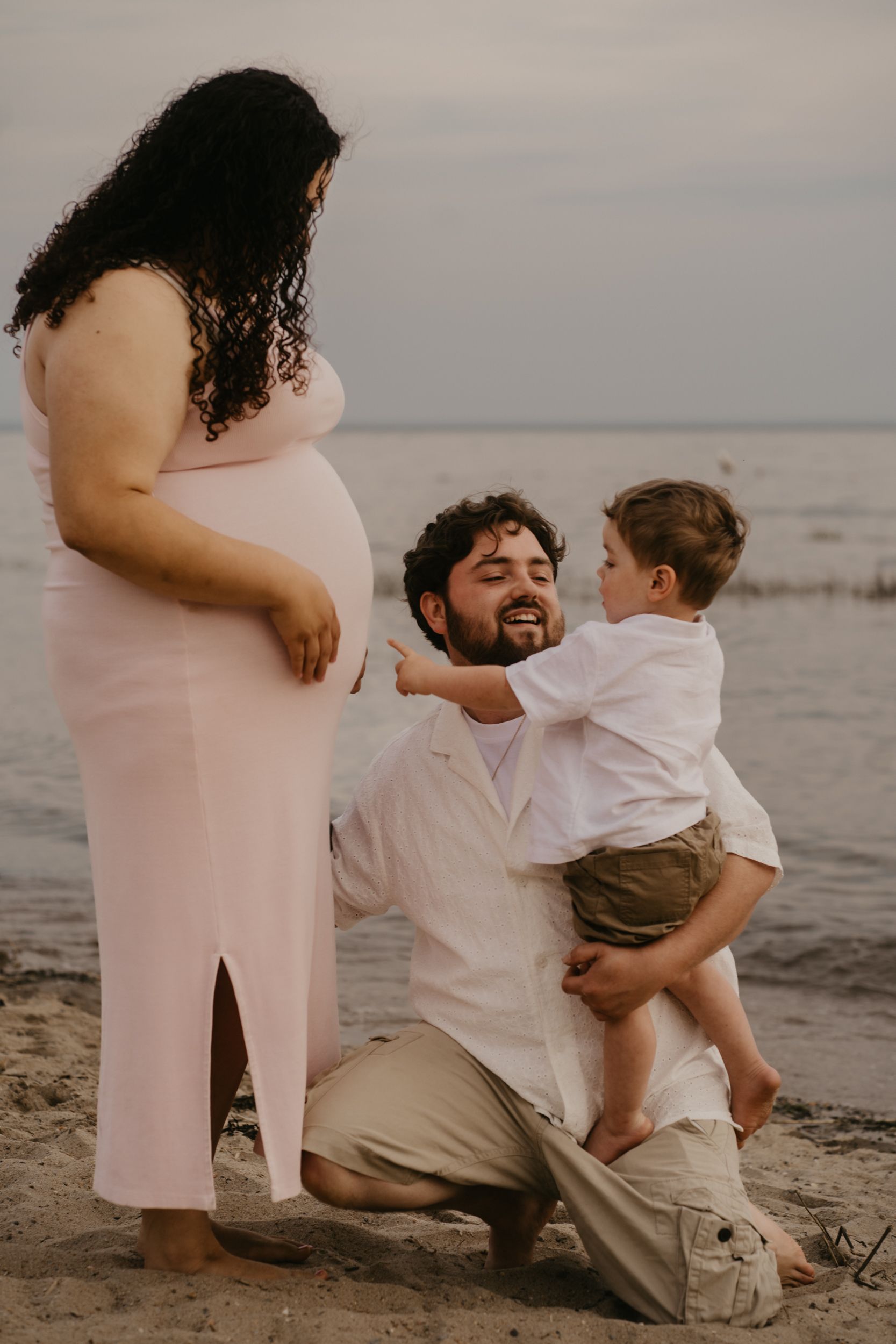 Family moment captured at beach during sunset with ocean in background. Connecticut.