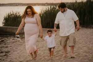 Family walks together on sandy beach during golden hour photoshoot.