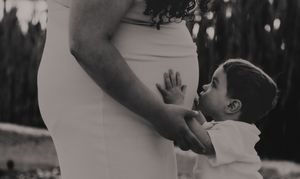 Close up of hands touching a pregnant belly in black and white.