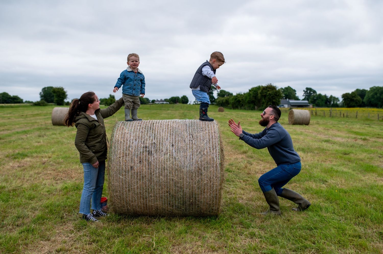 A group of people participate in a sack race competition on a sunny day in a grassy backyard.