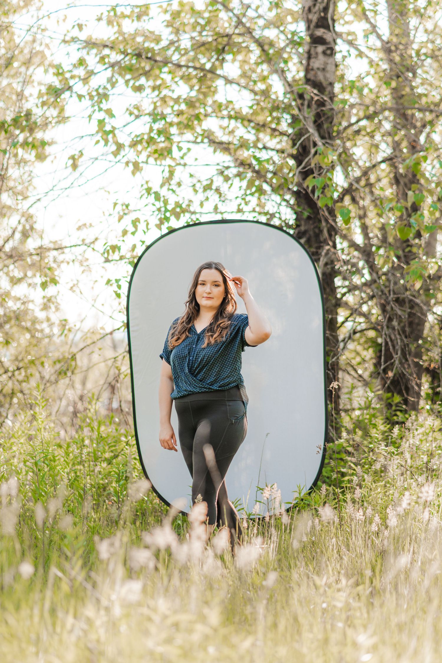 Full-body portrait of a woman walking toward the camera with a pop-up backdrop set in a sunny, wooded PNW location.