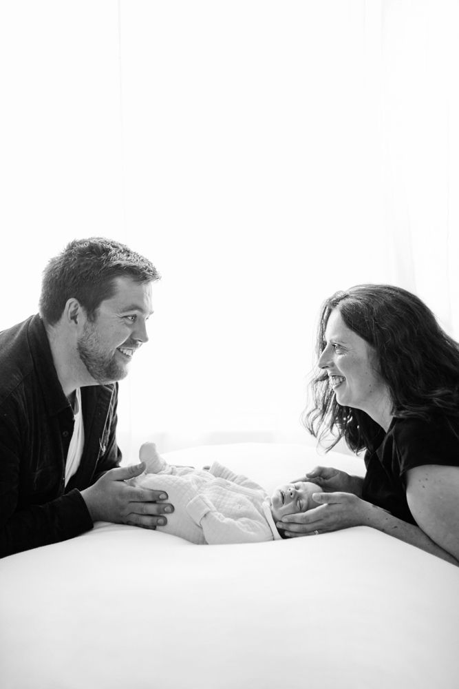 A four-panel sequence showing happy interaction between two people lying on a white bed or surface.