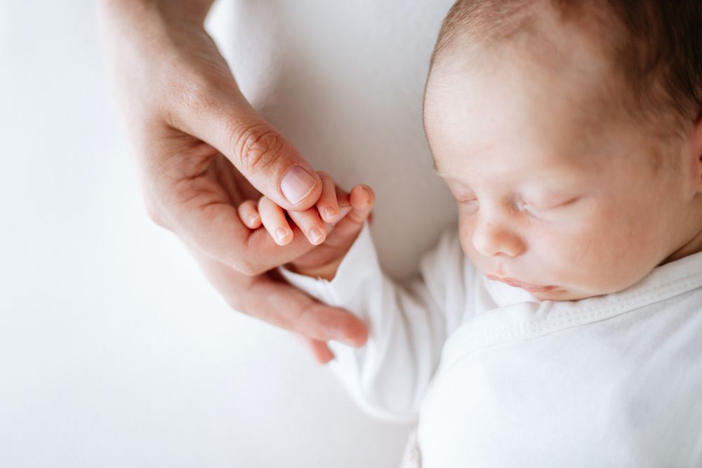 A series of black and white close-up photos showing gentle touches and tender moments between a parent and baby.