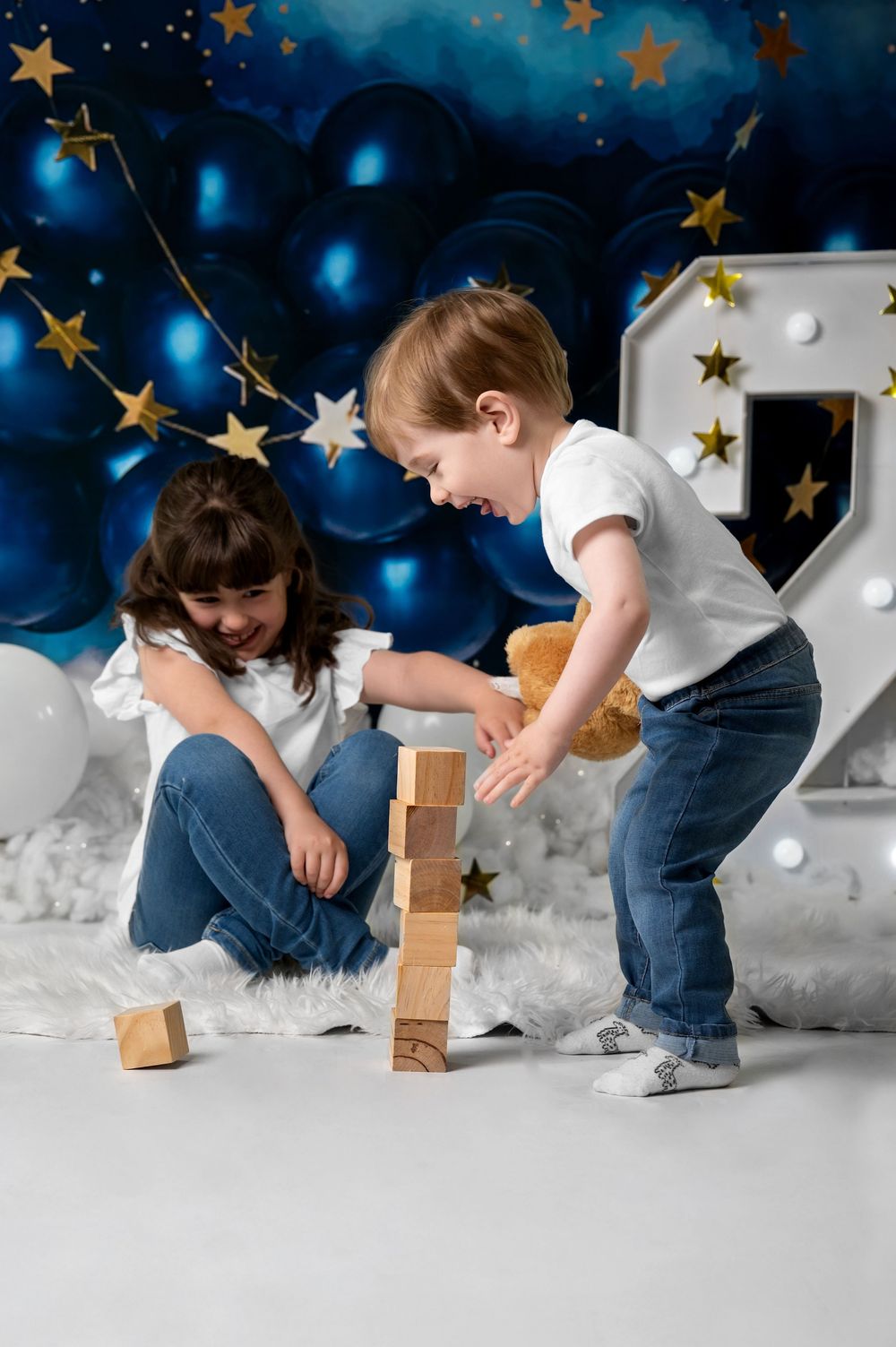 Two children playing with wooden blocks against magical starry blue background.