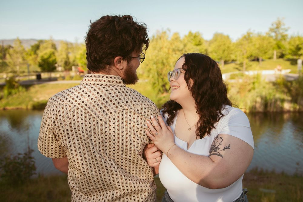 A romantic riverside couple photoshoot at sunset captures intimate moments in a natural outdoor setting against golden light.