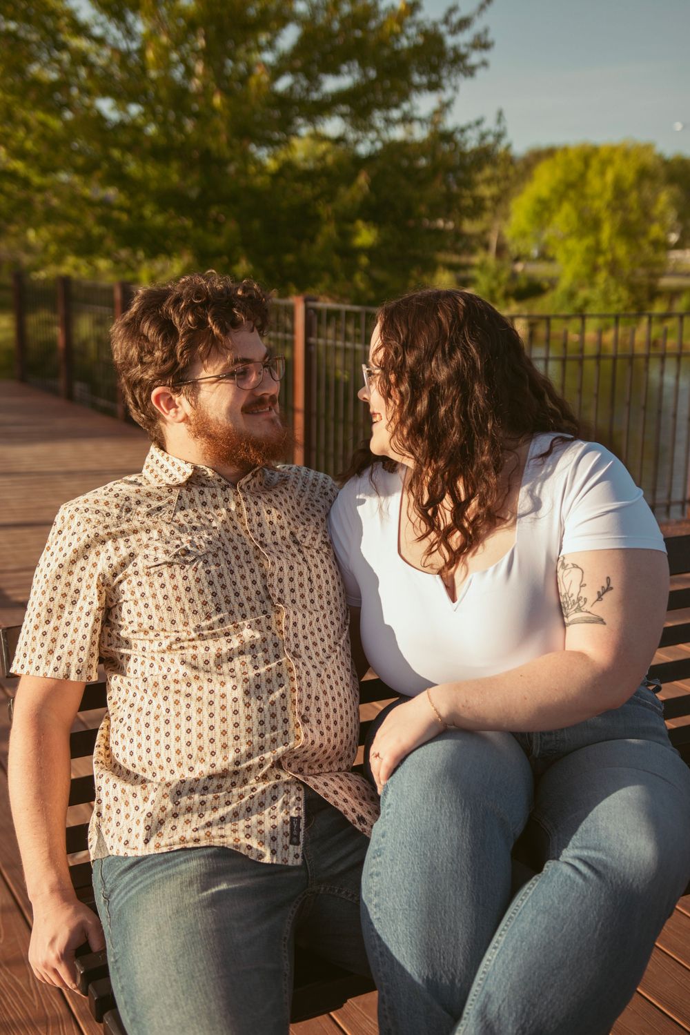 A couple sitting together on a bench and sharing a sweet moment in the warm evening light.