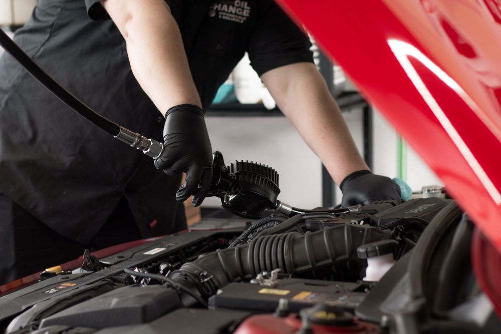 Detail shot of mechanic's hands working under the hood during service at West Richland oil shop