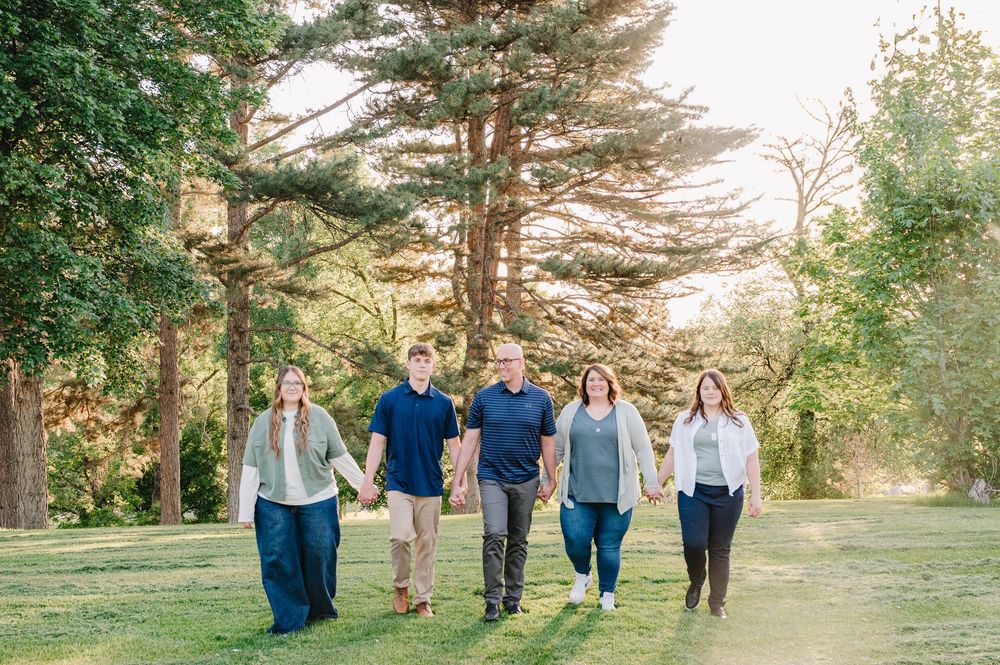 Group walking together through a sunlit park with tall pine trees creating a natural outdoor backdrop.