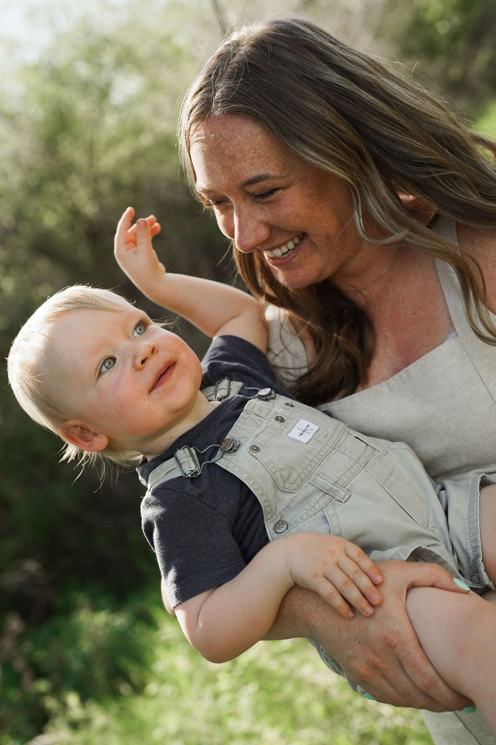 A joyful moment shared between parent and baby outdoors in natural sunlight with smiles and laughter.