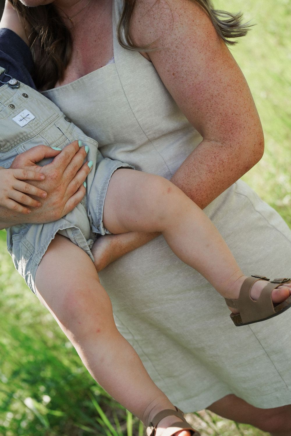 Sequence of photos showing arms holding and comforting a small baby in a beige outfit against a green outdoor background.