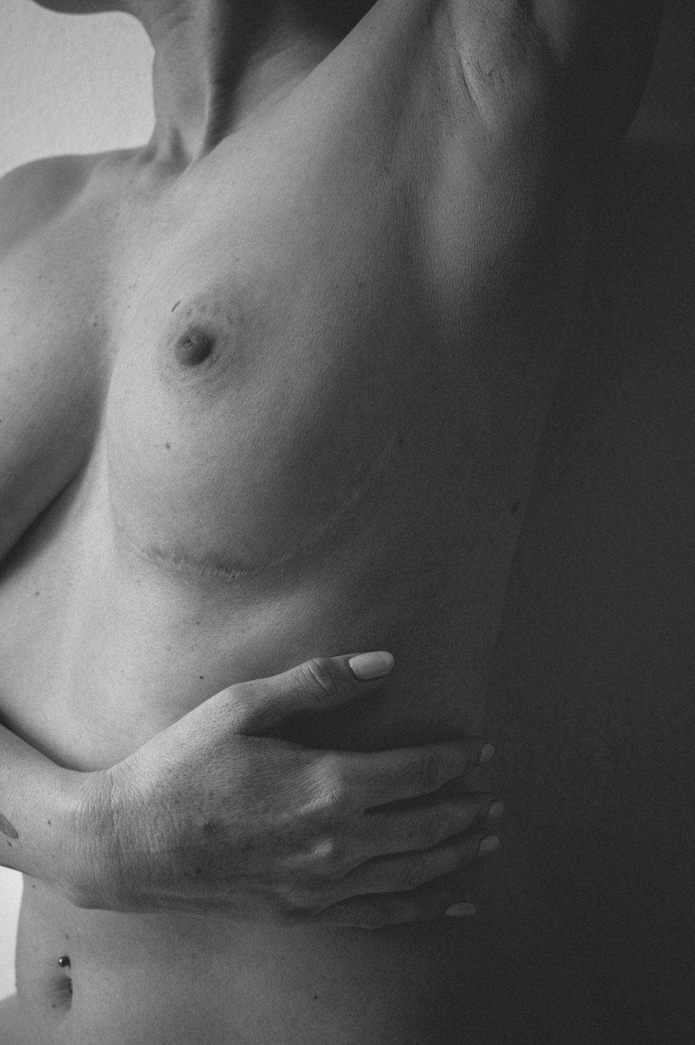 Black and white artistic portrait of torso with delicate hand placement, offering a sensual yet tasteful composition.