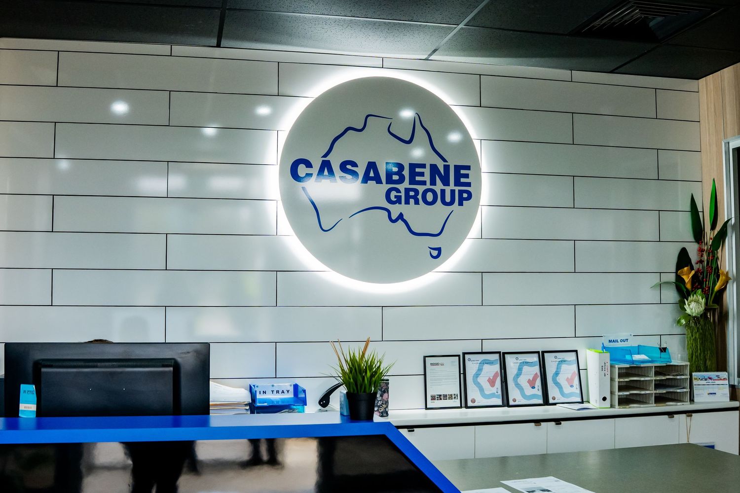 Modern office interior with white subway tile walls, illuminated logo signs, and sleek contemporary furniture.