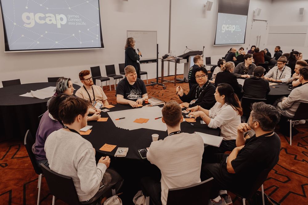 Business professionals gather at round tables for collaborative discussion and teamwork in a modern conference room setting.