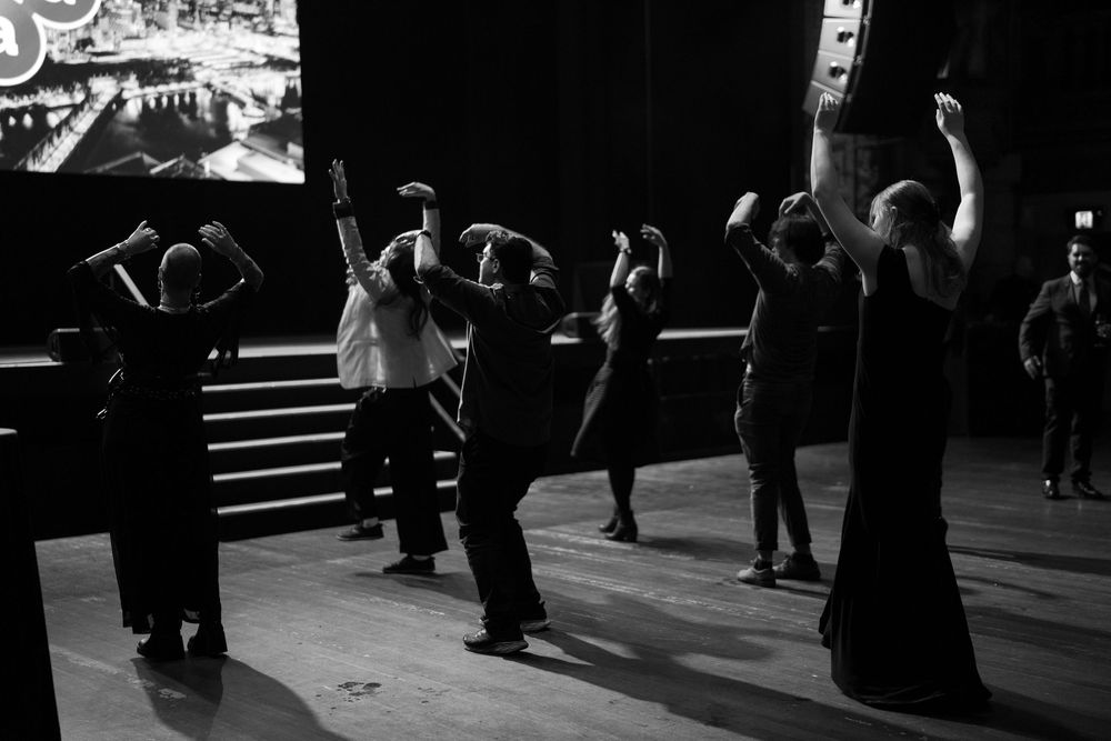 Black and white shot of people dancing in silhouette on a dark dance floor.