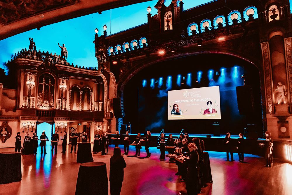 Panoramic view of an ornate ballroom with blue and red mood lighting and architectural details.
