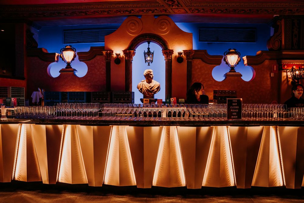 Softly illuminated wine glass goblet arrangements create an elegant amber glow at a formal event venue setting.