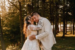 A romantic wedding photo captured during golden hour in a forest setting with sunlit trees in the background.