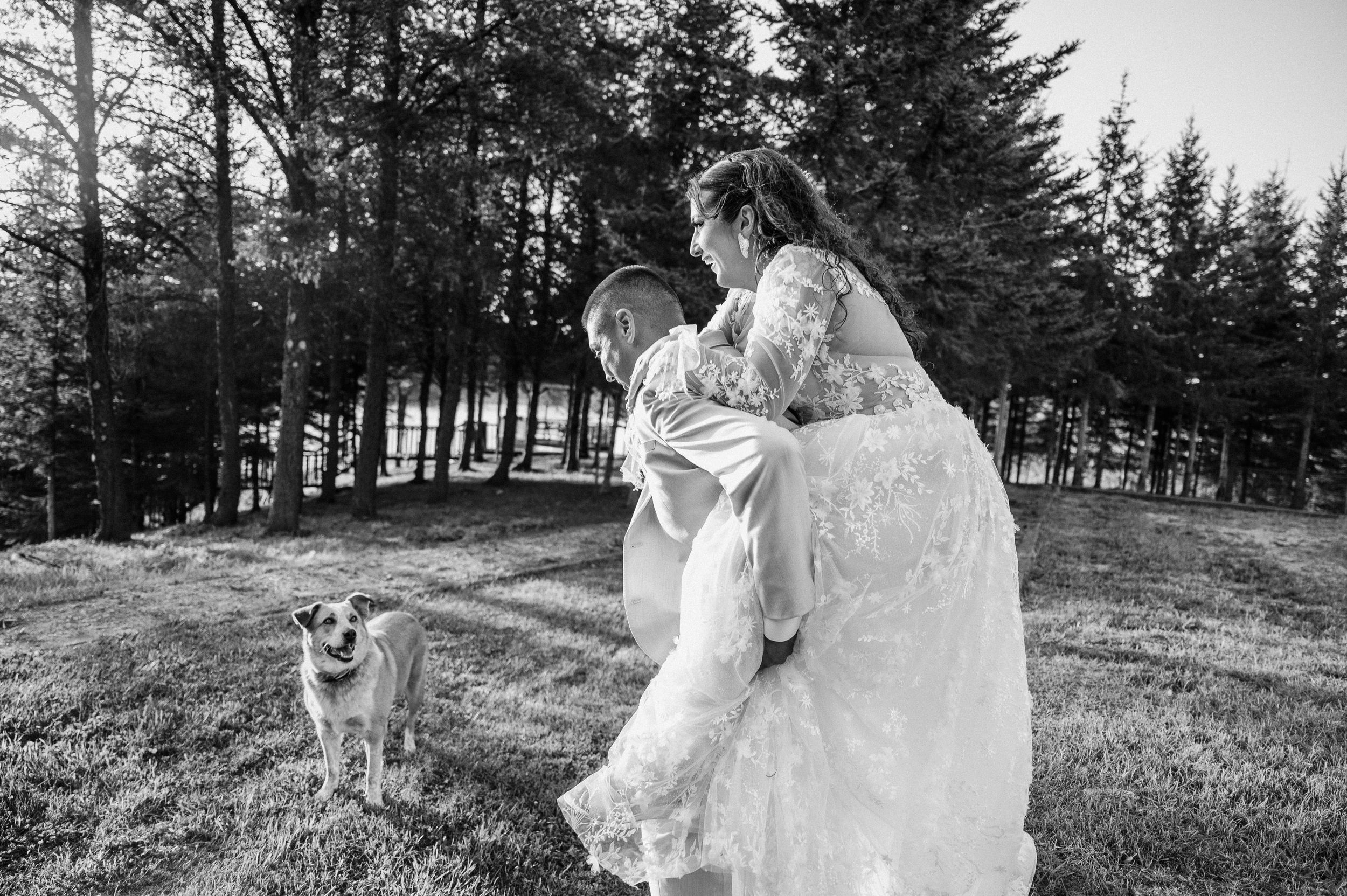 Romantic black and white photography series of a couple in formal attire amidst evergreen trees in a forest setting.