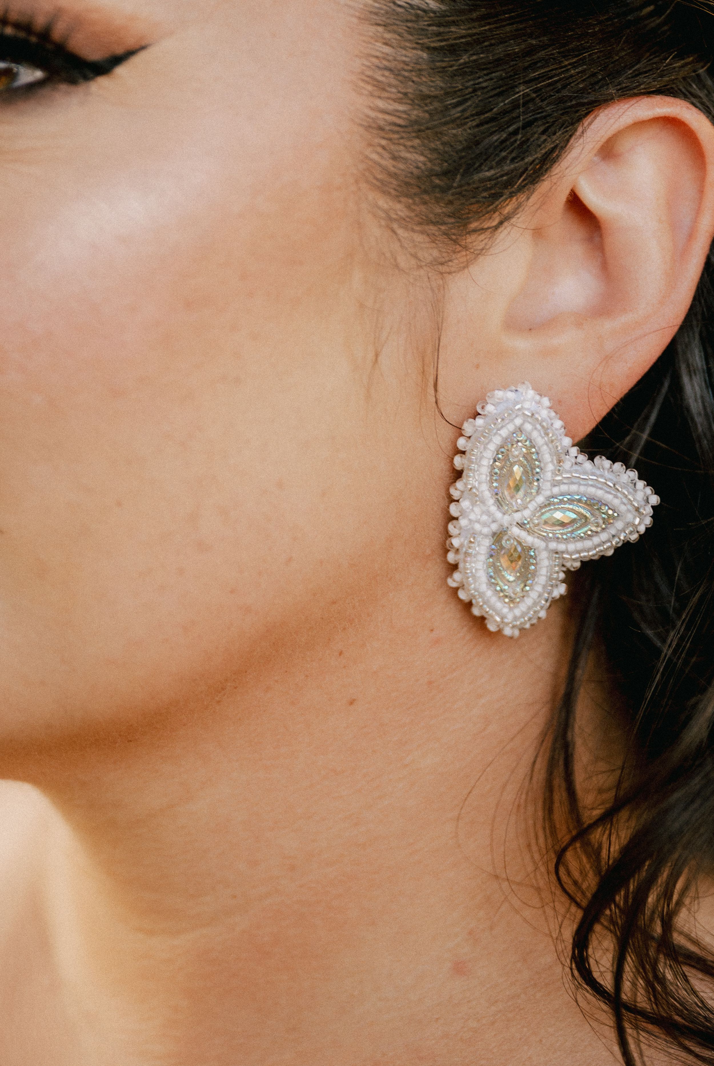 Crystal swirl stud earrings in silver with curved design shown from multiple angles on an ear.