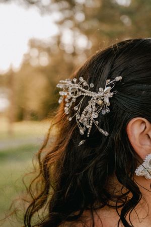 A delicate crystal hair accessory sparkles against dark hair in warm outdoor lighting.