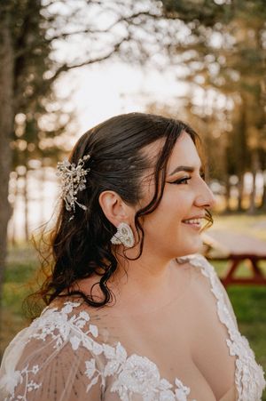 A close-up wedding portrait showing intricate lace details and delicate crystal hair accessories against autumn trees.