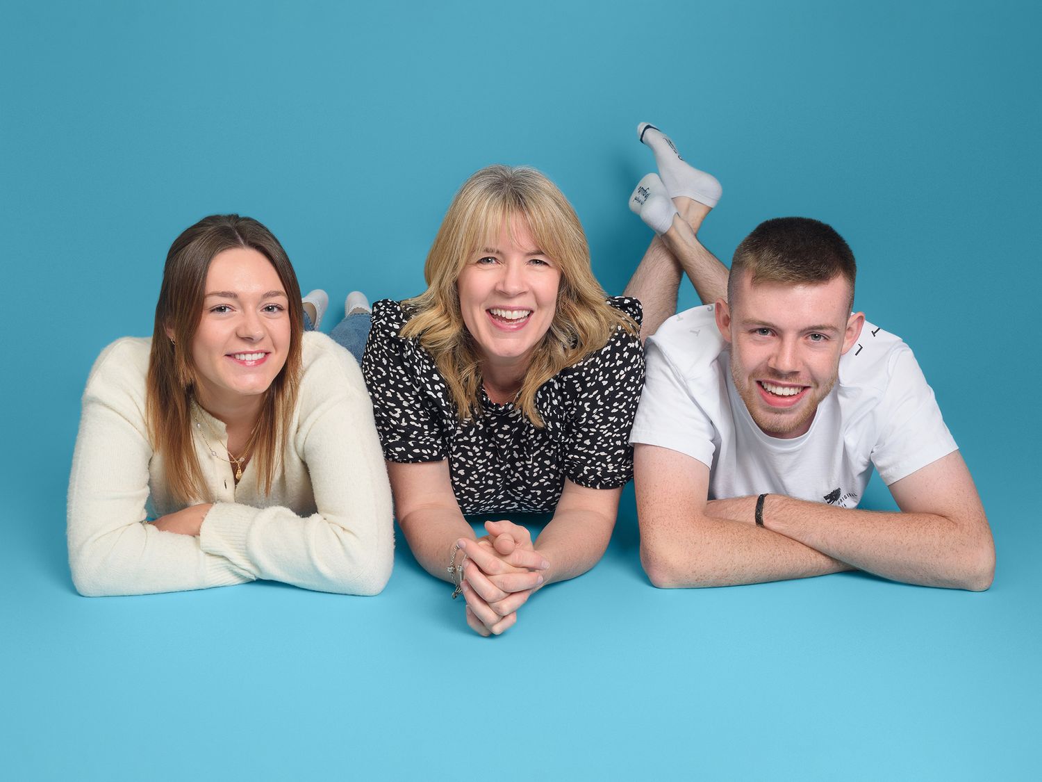 Three family members pose on a blue backdrop, showcasing photography gift vouchers from Abigail's Studio in Buckinghamshire.