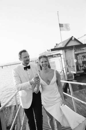 A couple shares a joyful moment together on a boat deck during a waterfront wedding celebration.