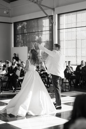 A couple dances together on a black and white checkered floor at their wedding reception.