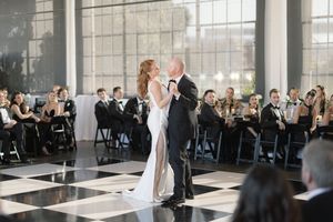 A formal dance taking place on a black and white checkered floor with guests watching from their seats.