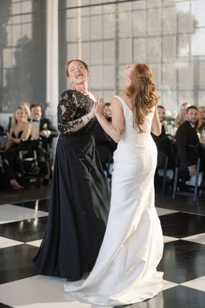 Wedding celebration moment with dancing figures in white and black formal attire on a checkered dance floor.