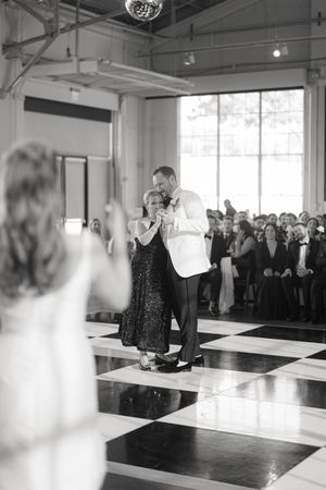 Black and white photo of a dance on a checkered floor during an elegant celebration.