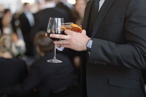Close-up of hands holding a wine glass at a formal event.