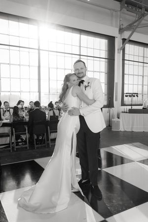 Couples dancing in formal attire on a black and white dance floor in a bright venue.