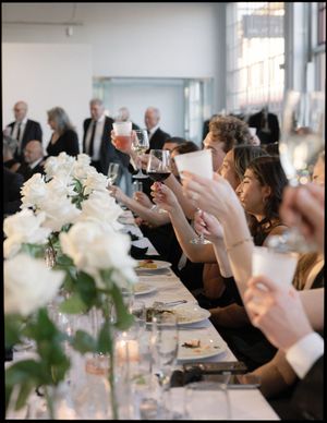 Wedding guests taking photos during dinner at elegant white-tablecloth reception.
