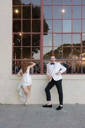 A couple poses playfully by a window wall during a wedding photoshoot creating a mirror-like sequence.