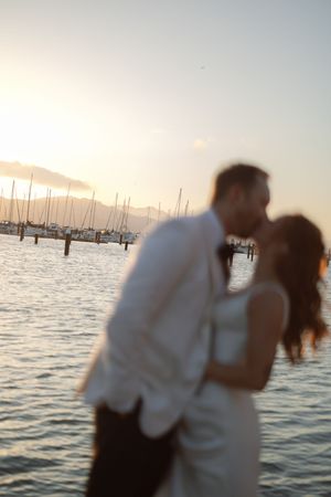 Romantic sunset silhouette at a marina with boats in the background.
