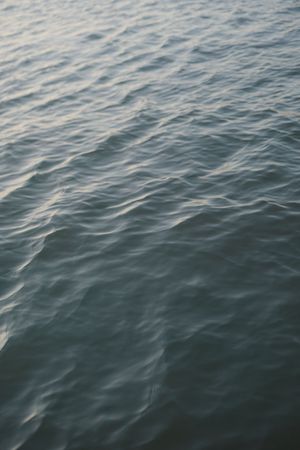 Peaceful rippling ocean water surface at dusk with gentle waves.
