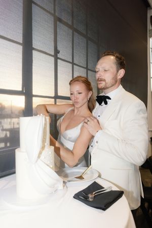 Couple sharing cake during their wedding reception in a bright modern space.
