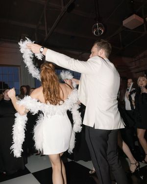 A couple dancing at a formal event, with the woman wearing white and the man in black formal attire.