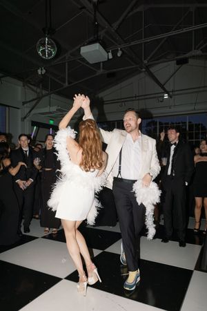 Couple sharing a romantic dance with the bride wearing white and feathers at their wedding reception.