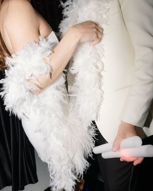 A dress adorned with elegant white feather details and a formal white suit at what appears to be a special event.