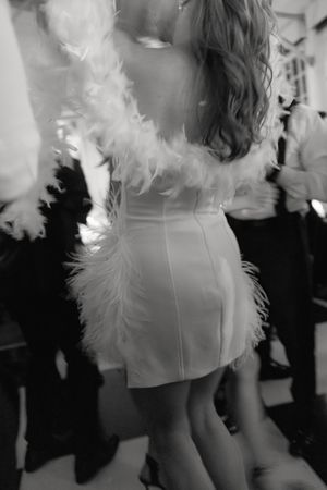 A person wearing a white dress with feather details dances at a formal event.