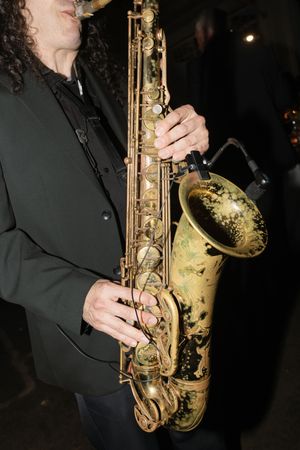 Close-up shots of a saxophone player performing in a dark setting with dramatic lighting.