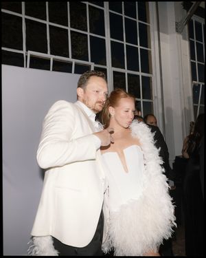 A couple shares a joyful moment together wearing coordinating white formal attire.