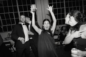 Black and white photo of people dancing and celebrating at a party with joyful expressions in formal attire.